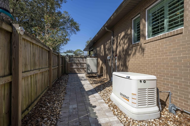 view of side of home with a gate, brick siding, and a fenced backyard