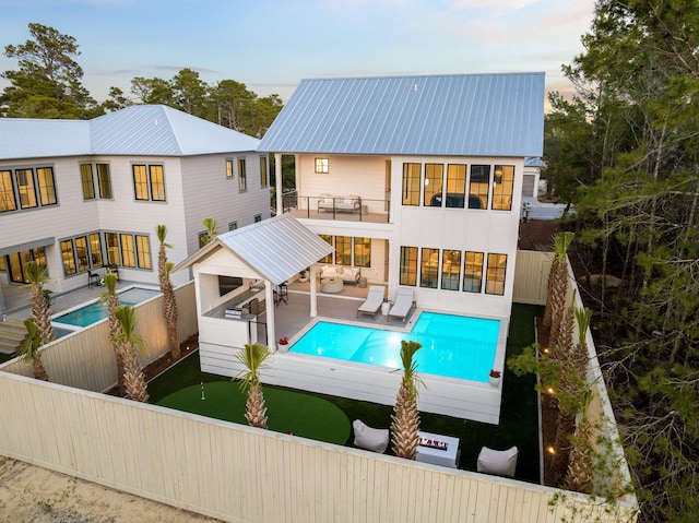 back of house featuring a balcony, an outdoor living space, and a patio