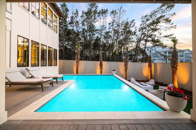 pool at dusk with a wooden deck