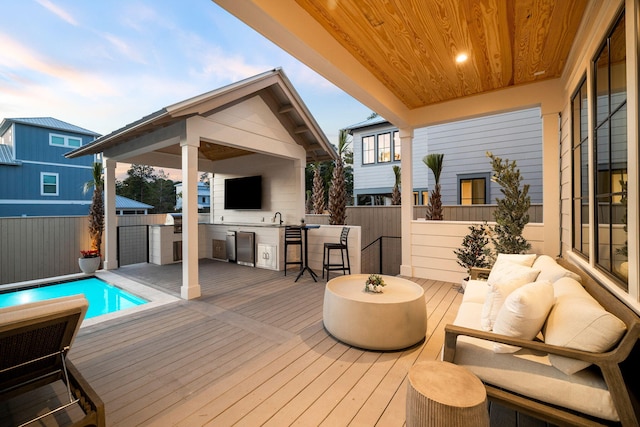 wooden deck featuring a fenced in pool, exterior kitchen, and a wet bar