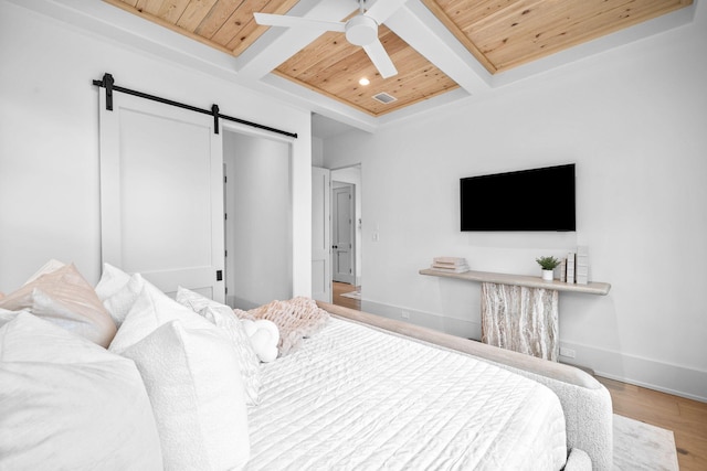 bedroom with wood ceiling, wood-type flooring, a barn door, and beamed ceiling