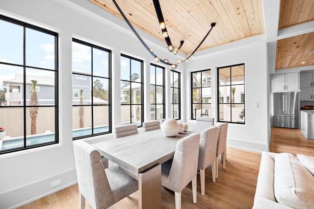 dining area with an inviting chandelier, a wealth of natural light, light hardwood / wood-style flooring, and wooden ceiling