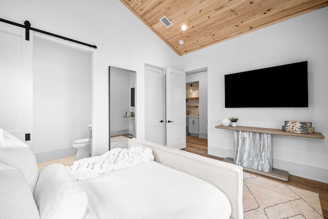 bedroom featuring wood ceiling, light hardwood / wood-style flooring, high vaulted ceiling, ensuite bathroom, and a barn door