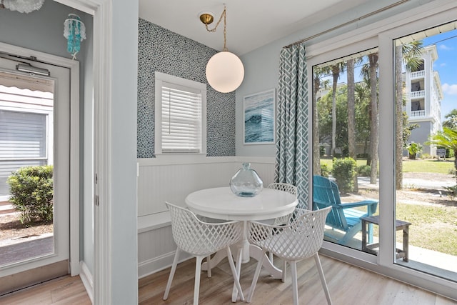 dining room with wainscoting, wood finished floors, and wallpapered walls