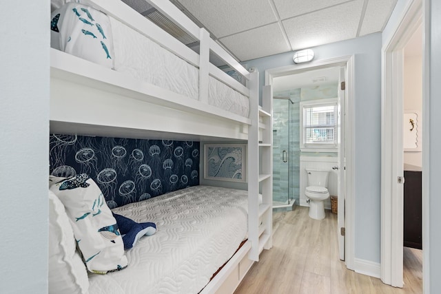 bedroom featuring a paneled ceiling, connected bathroom, and wood finished floors