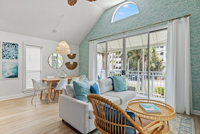 living room featuring lofted ceiling, light wood finished floors, baseboards, and a wealth of natural light