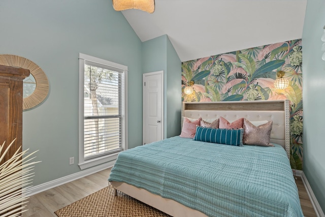 bedroom with high vaulted ceiling, an accent wall, baseboards, and wood finished floors