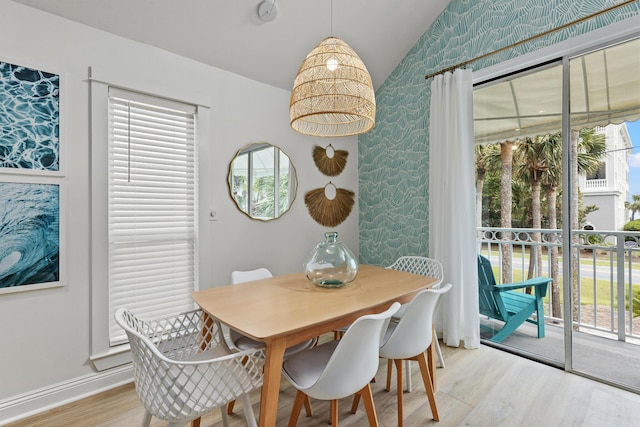 dining space featuring vaulted ceiling, baseboards, light wood-style flooring, and wallpapered walls