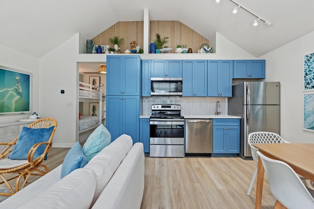 kitchen featuring blue cabinetry, light countertops, appliances with stainless steel finishes, a sink, and light wood-type flooring