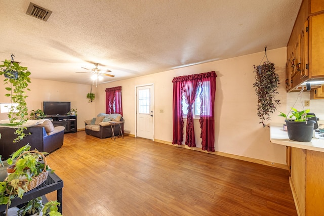 living room featuring wood-type flooring, ceiling fan, and a textured ceiling