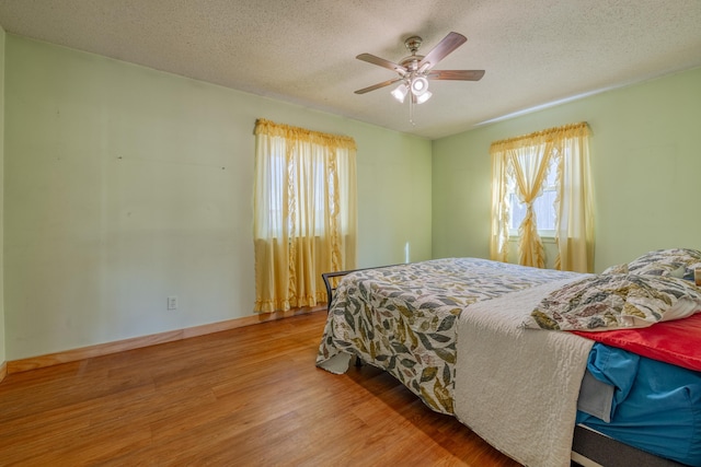 bedroom featuring ceiling fan, hardwood / wood-style flooring, and a textured ceiling