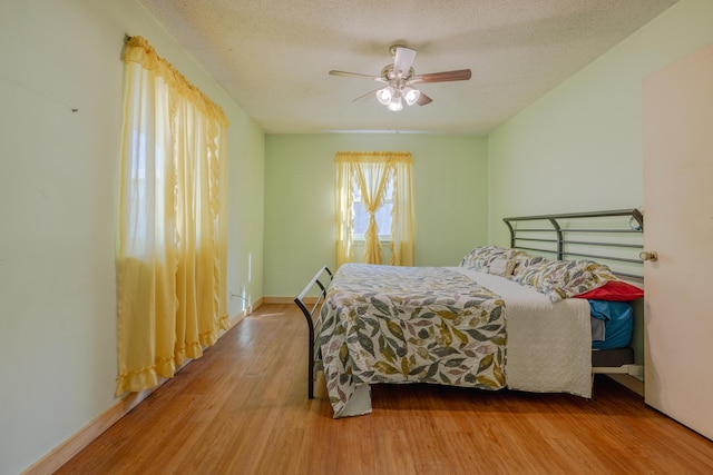 bedroom with ceiling fan, wood-type flooring, and a textured ceiling