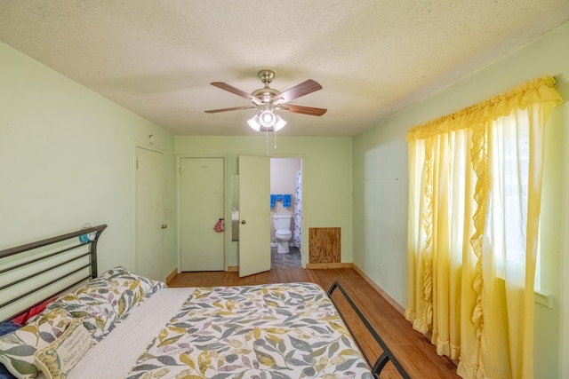 bedroom featuring ceiling fan, ensuite bath, light hardwood / wood-style floors, and a textured ceiling