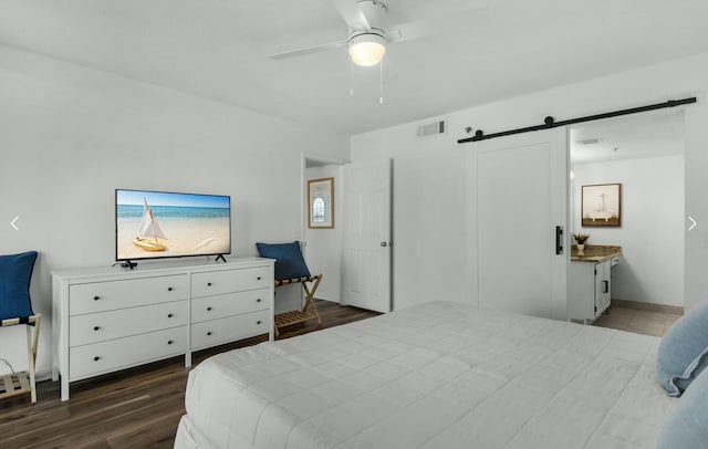 bedroom featuring dark wood-type flooring, a barn door, and ceiling fan