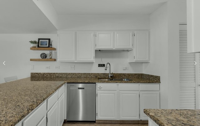 kitchen featuring white cabinetry, sink, stainless steel dishwasher, and dark stone counters