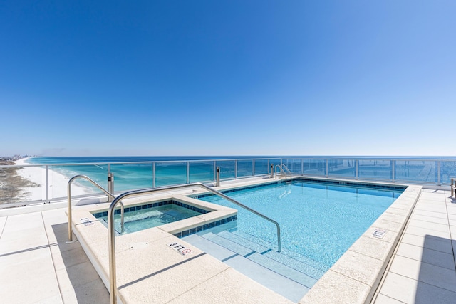 view of pool with a water view and a hot tub