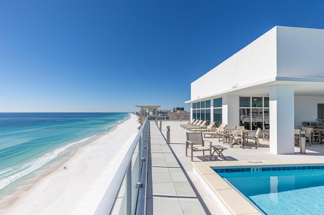 pool featuring a patio, a water view, and a view of the beach