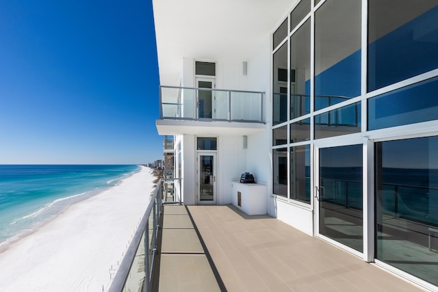 balcony featuring a view of the beach and a water view