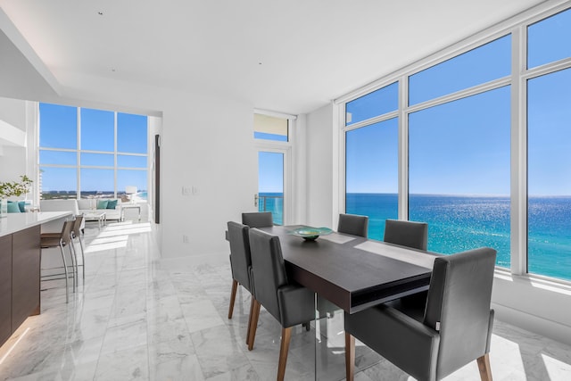 dining space featuring a water view and marble finish floor