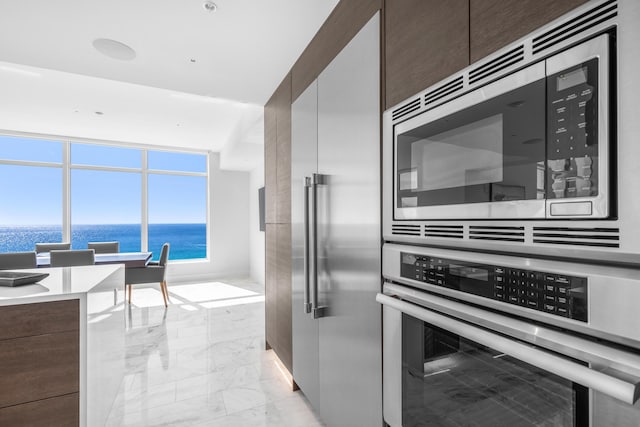 kitchen featuring appliances with stainless steel finishes, marble finish floor, dark brown cabinetry, and modern cabinets