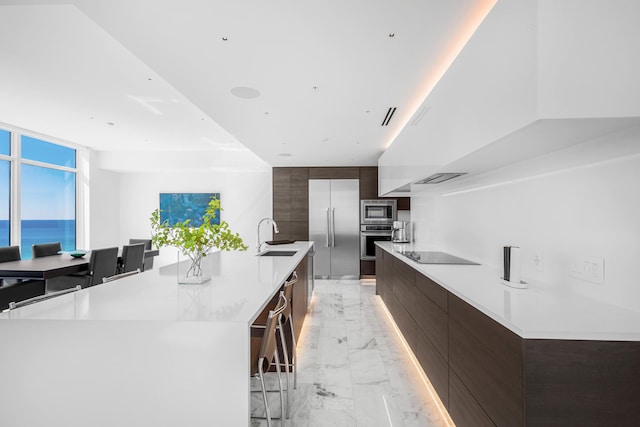 kitchen with marble finish floor, modern cabinets, a sink, dark brown cabinetry, and built in appliances