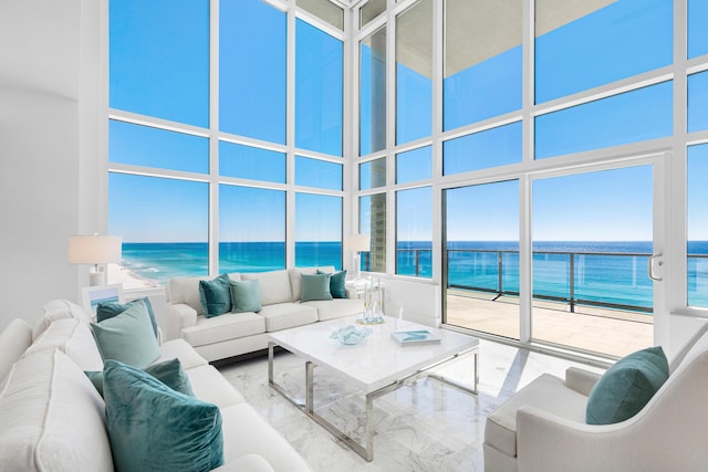 living area featuring marble finish floor, a water view, and a towering ceiling