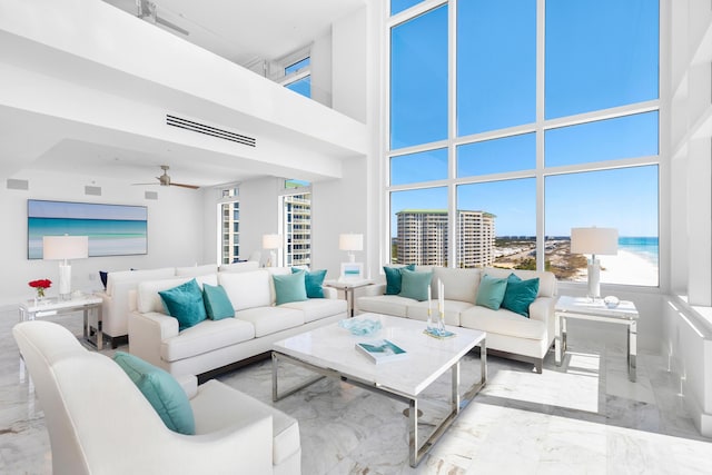 living area with marble finish floor, ceiling fan, a high ceiling, and visible vents