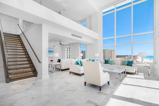 living room featuring ceiling fan, a high ceiling, visible vents, stairs, and marble finish floor