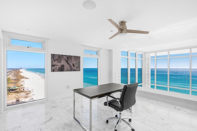 home office with a water view, marble finish floor, and ceiling fan