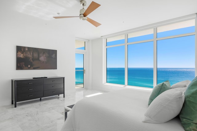 bedroom featuring ceiling fan, marble finish floor, expansive windows, and a water view