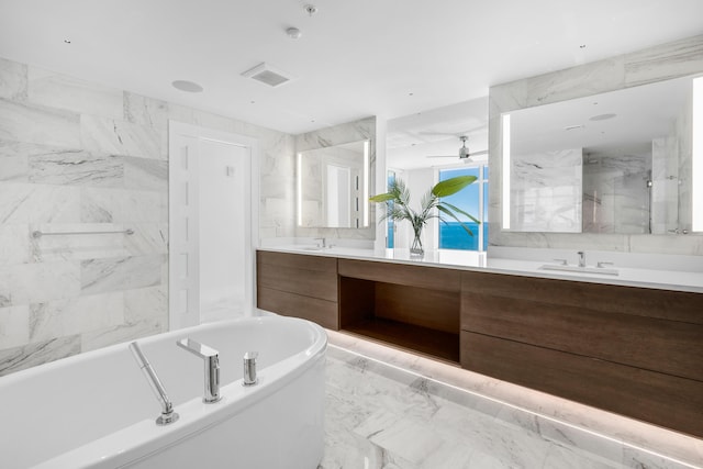 full bathroom featuring a sink, marble finish floor, double vanity, and a freestanding tub