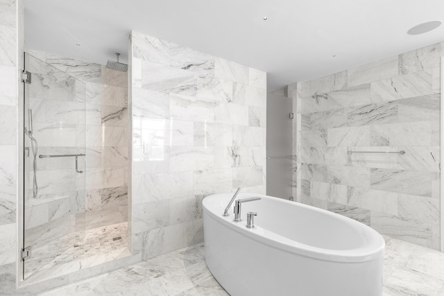 bathroom with stone wall, a freestanding tub, tile walls, marble finish floor, and a marble finish shower