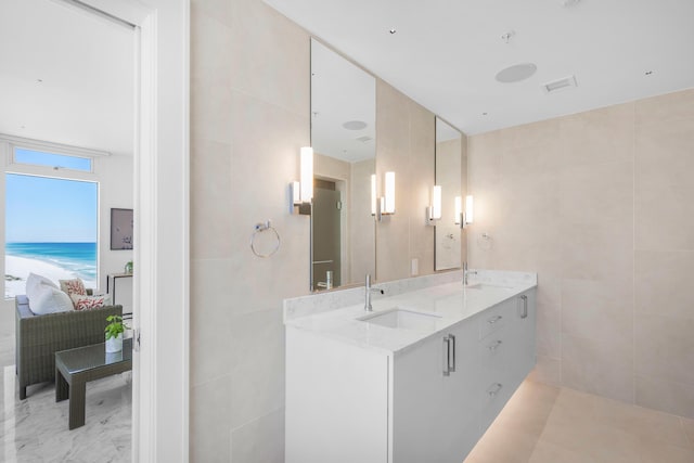 full bath featuring ensuite bathroom, a sink, and tile walls