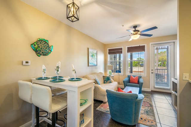 living area with light tile patterned flooring, a ceiling fan, and baseboards