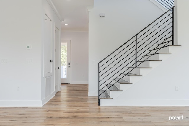 entryway featuring crown molding and light wood-type flooring