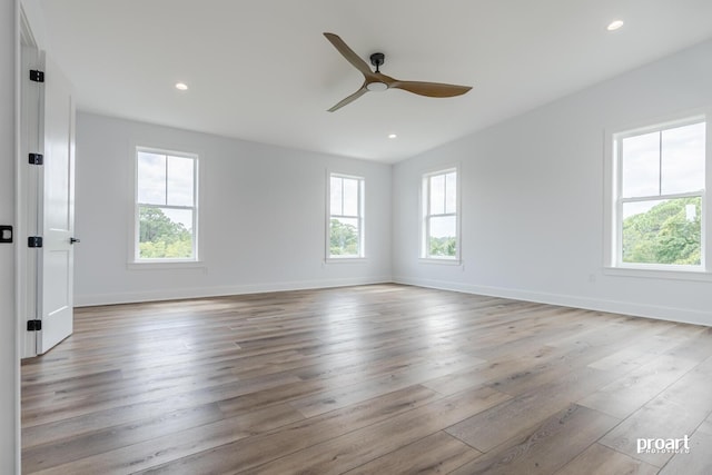 spare room featuring ceiling fan, a wealth of natural light, and light wood-type flooring