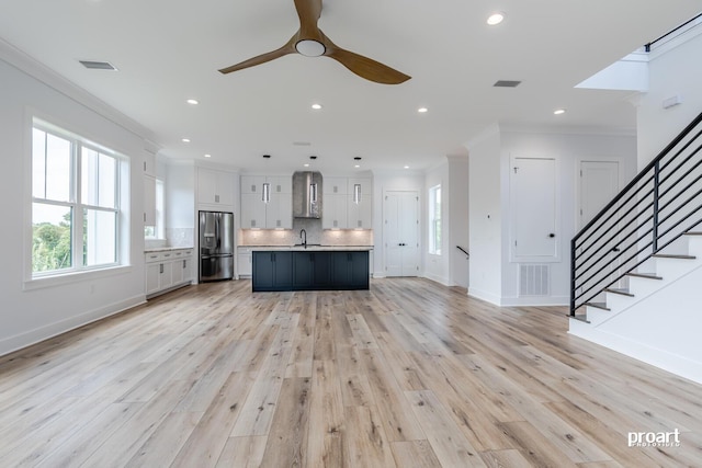 unfurnished living room featuring ceiling fan, ornamental molding, sink, and light wood-type flooring