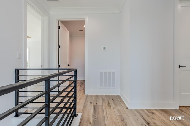 corridor featuring crown molding and light hardwood / wood-style flooring