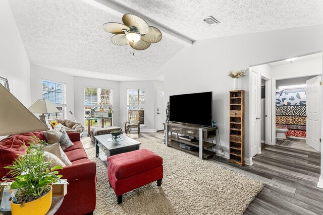 living room featuring ceiling fan, dark hardwood / wood-style floors, vaulted ceiling with beams, and a textured ceiling