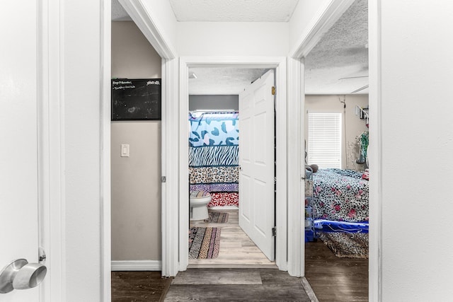 hallway featuring wood-type flooring and a textured ceiling