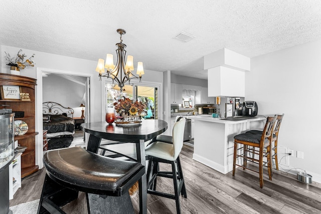 dining area featuring dark hardwood / wood-style flooring, a textured ceiling, and an inviting chandelier