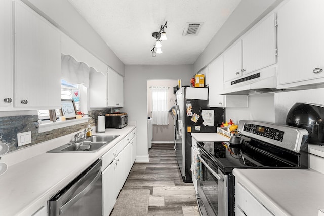 kitchen featuring sink, white cabinetry, wood-type flooring, a textured ceiling, and stainless steel appliances
