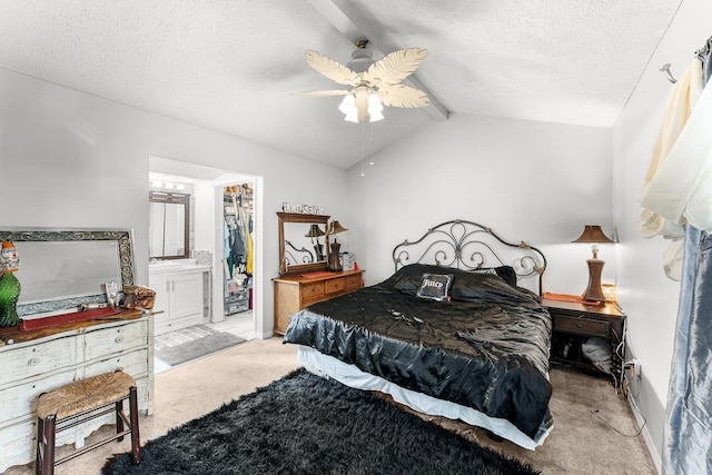 bedroom featuring ceiling fan, vaulted ceiling with beams, a textured ceiling, light carpet, and a walk in closet