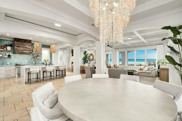 dining space with decorative columns, arched walkways, stone tile flooring, beamed ceiling, and a chandelier