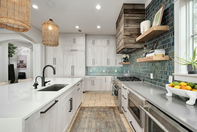 kitchen with stone tile flooring, a sink, appliances with stainless steel finishes, and open shelves