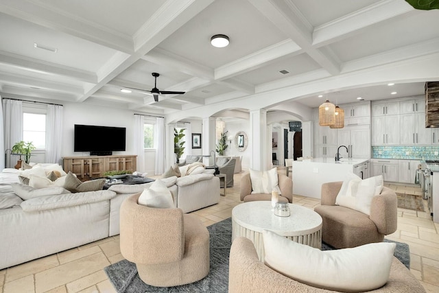 living area with arched walkways, beam ceiling, a healthy amount of sunlight, and ornate columns