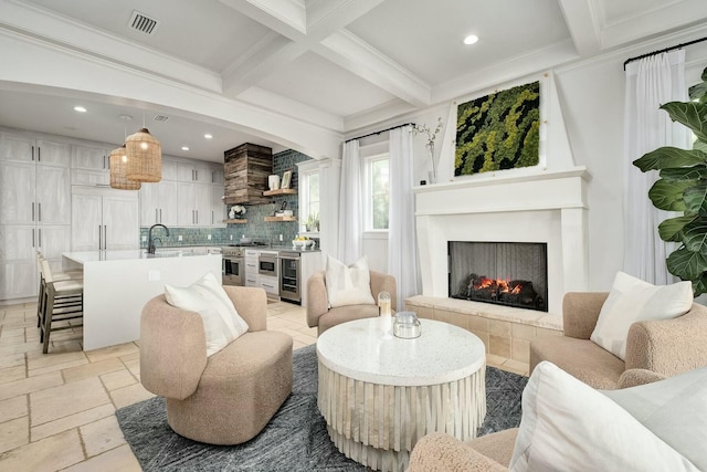 living room with beamed ceiling, visible vents, coffered ceiling, stone tile floors, and a warm lit fireplace