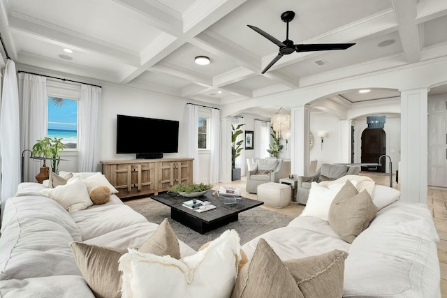 living area featuring decorative columns, arched walkways, beam ceiling, and a ceiling fan