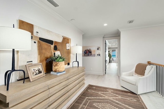 living area with visible vents, baseboards, wood finished floors, and crown molding