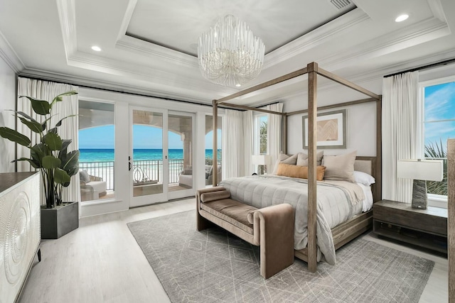 bedroom with multiple windows, a raised ceiling, and an inviting chandelier